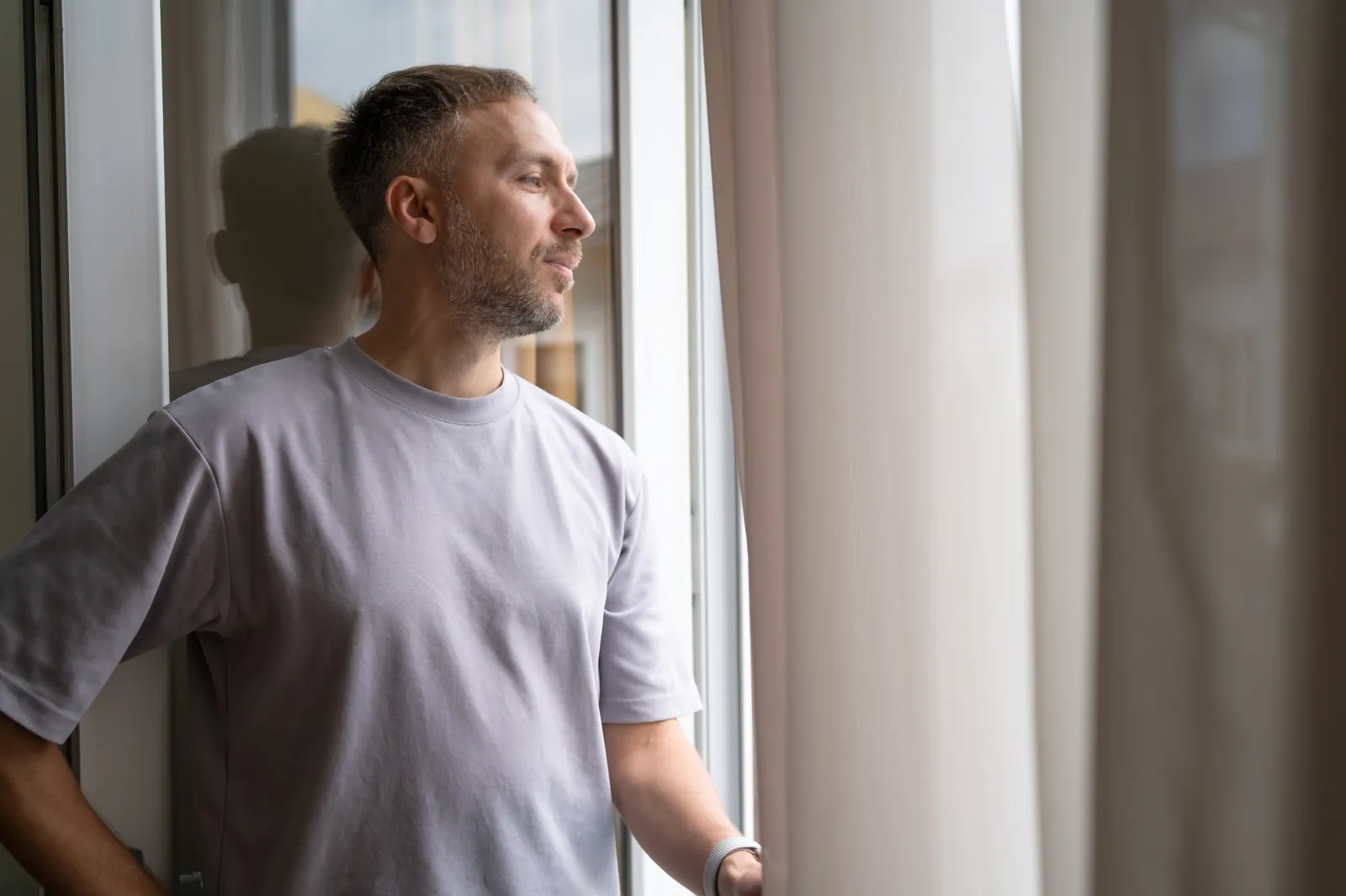 Mann blickt nachdenklich aus dem Fenster