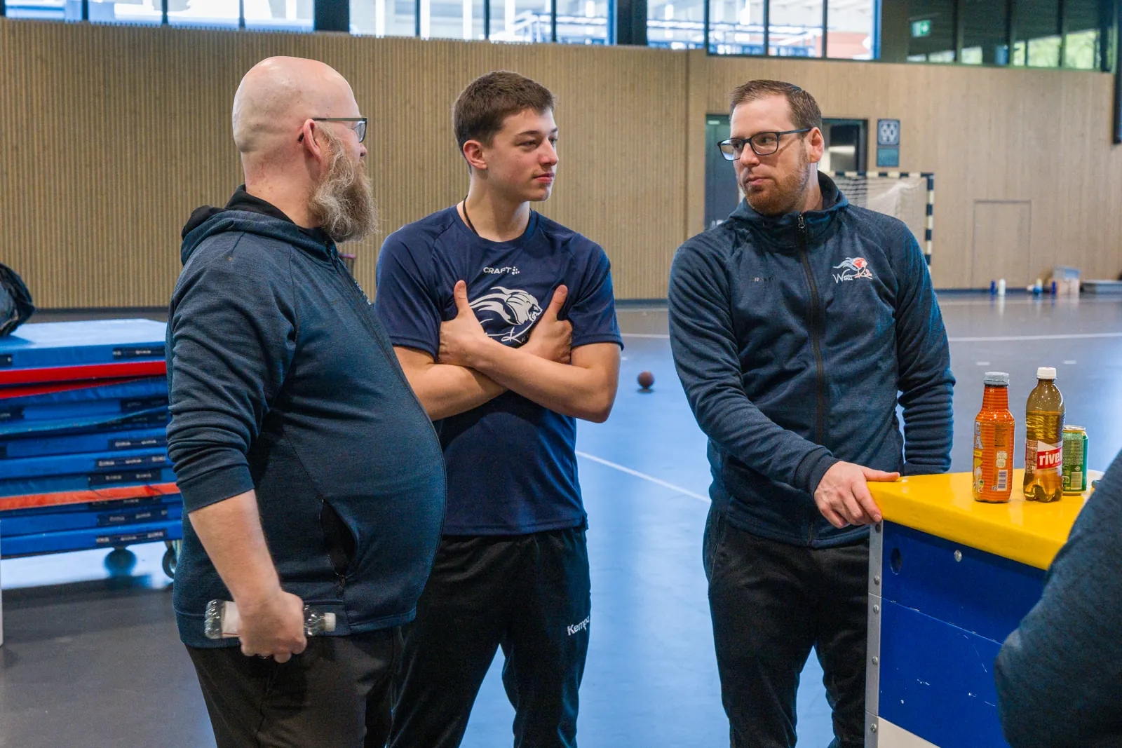 Patrick Bösch im Austausch mit einem jungen Spieler und einem Trainerkollegen in der Halle